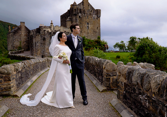Bride and groom looking off into distance with castle in background